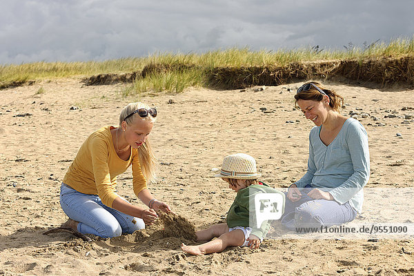 France  Britanny  Sainte-Anne-la-Palud  mother and her two daughters sitting on beach dune