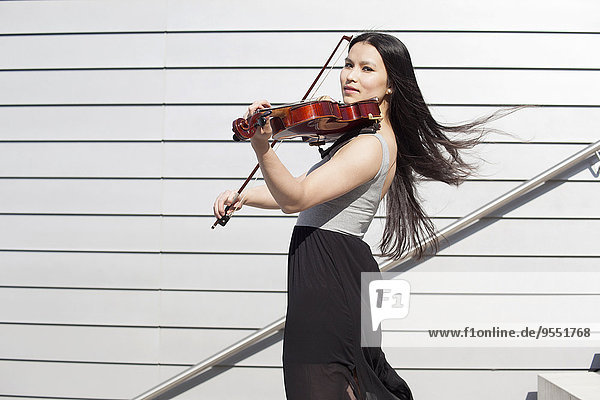 Portrait of young female Asian playing violin on stairs