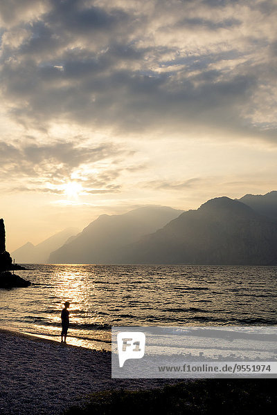 Italy  Veneto  Malcesine  Boy standing at Lake Garda in evening light