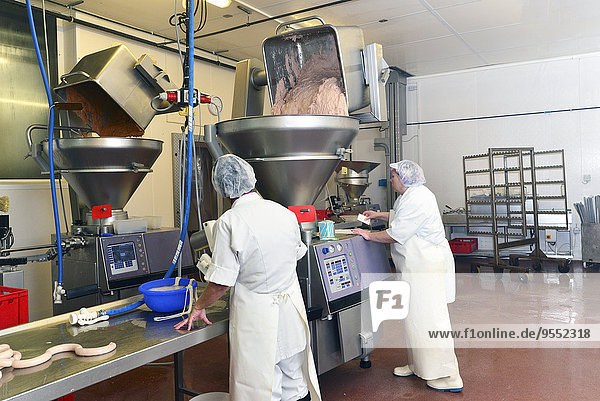 Frau bedient Füllmaschine mit Fleischwurst in einer Metzgerei
