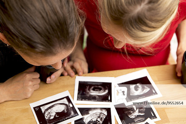 Schwangere Frau und Freundin beim Betrachten von Ultraschalluntersuchungen
