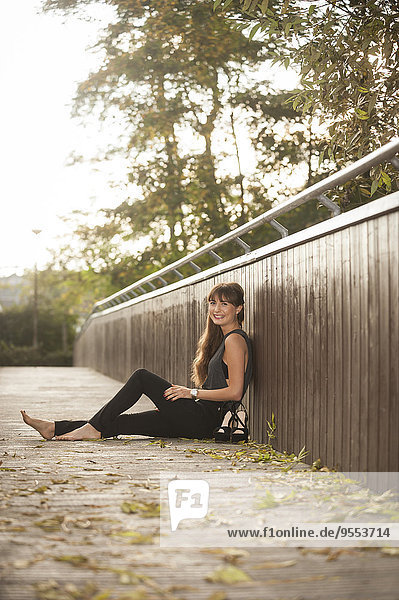 Lächelnde junge Frau entspannt auf einem Steg