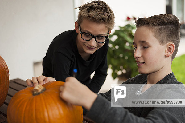 Zwei Jungen bereiten einen Kürbis für die Halloween-Laterne vor.