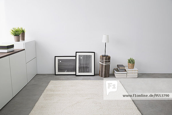 Sideboard  Bilderrahmen  Bücherstapel  Teppich und Tischlampe im modernen Wohnzimmer