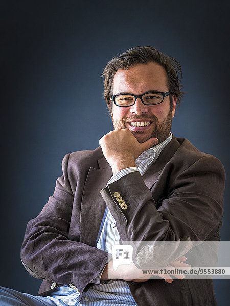 Portrait of smiling man with full beard wearing glasses in front of dark background