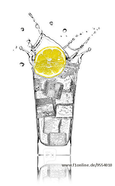Glas mit Sodawasser  Eiswürfeln und Zitronenscheibe vor weißem Hintergrund