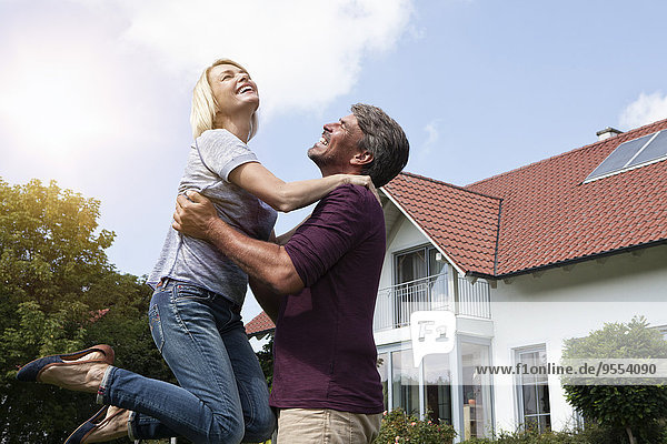 Happy man lifting up woman in garden