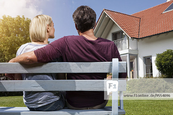 Rear view of mature couple sitting on bench in garden