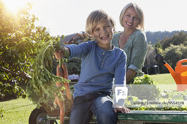 Junge mit Mutter im Garten mit Karottenstrauß