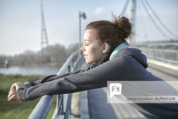 Junge Frau mit Pulsmesser entspannt nach dem Joggen