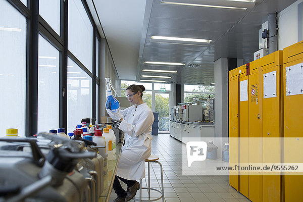 Junge Wissenschaftlerin mit Glaskolben in einem Chemielabor