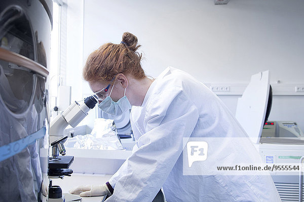 Junge Naturwissenschaftlerin beim Blick durchs Mikroskop im Biochemie-Labor
