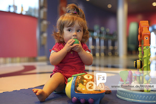 Baby girl playing with toys in a playroom of cruise liner