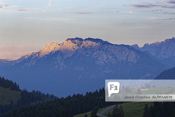 Deutschland  Bayern  Oberbayern  Mangfallgebirge  Blick auf die Kapelle am Sudelfeld  im Hintergrund Zahmer Kaiser in Österreich am Abend
