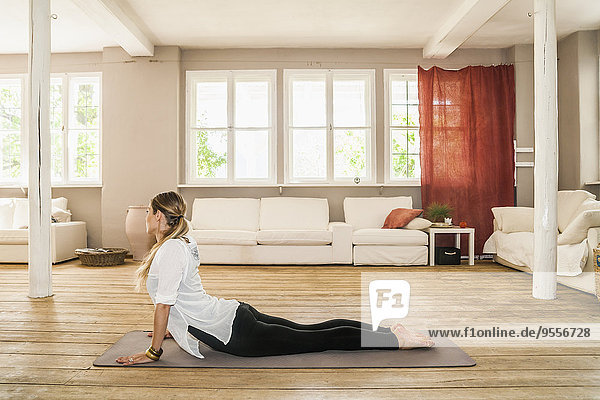 Frau praktiziert Yoga im Wohnzimmer