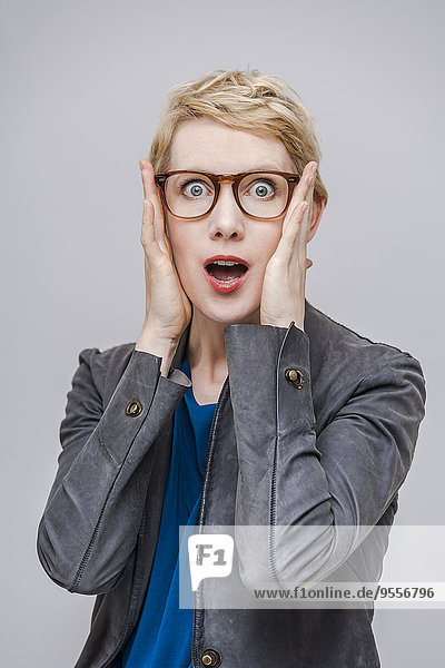 Portrait of frightened blond woman with hands on her face