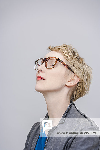 Blond woman with closed eyes in front of grey background