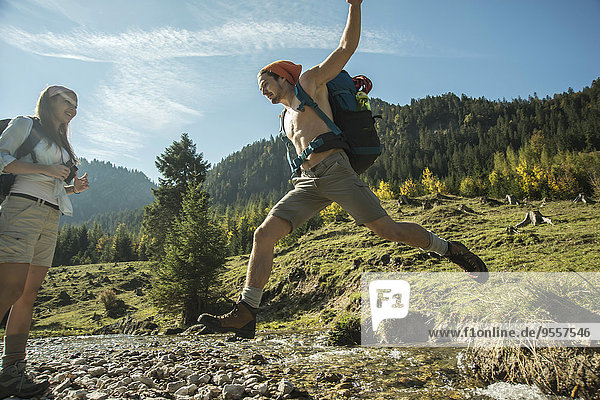 Österreich  Tirol  Tannheimer Tal  zwei junge Wanderer beim Überqueren des Wassers