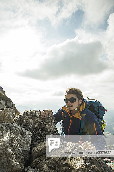 Austria  Tyrol  Tannheimer Tal  young man climbing on rock