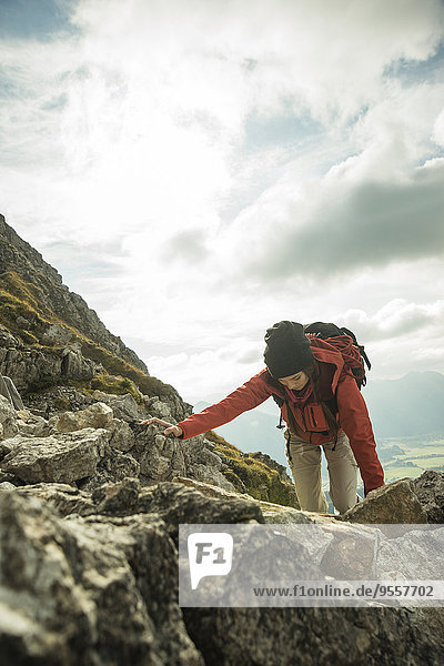 Österreich  Tirol  Tannheimer Tal  junge Frau klettert auf Felsen