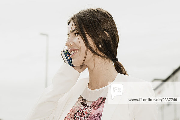 Lächelnde junge Geschäftsfrau telefoniert mit Smartphone