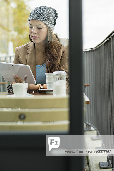 Junge Frau sitzt auf dem Bürgersteig Cafe mit digitalem Tablett