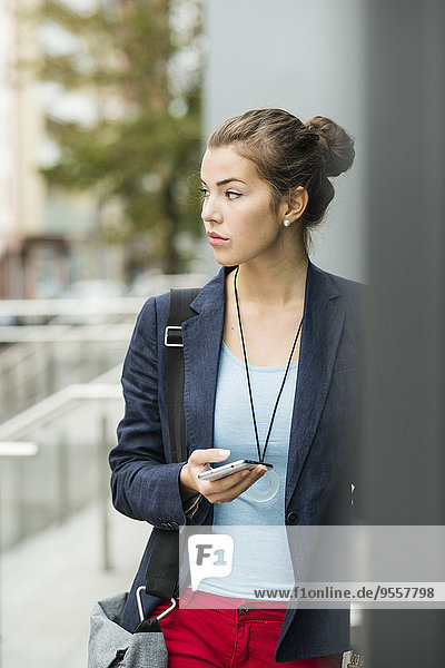 Young serious looking woman with smartphone waiting