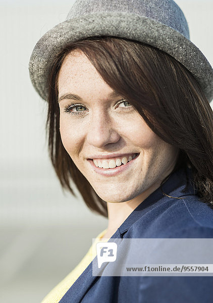 Porträt einer lächelnden jungen Frau mit Hut
