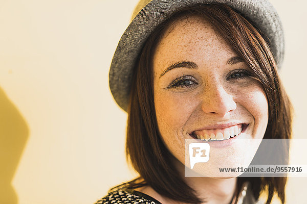 Porträt einer lächelnden jungen Frau mit Hut