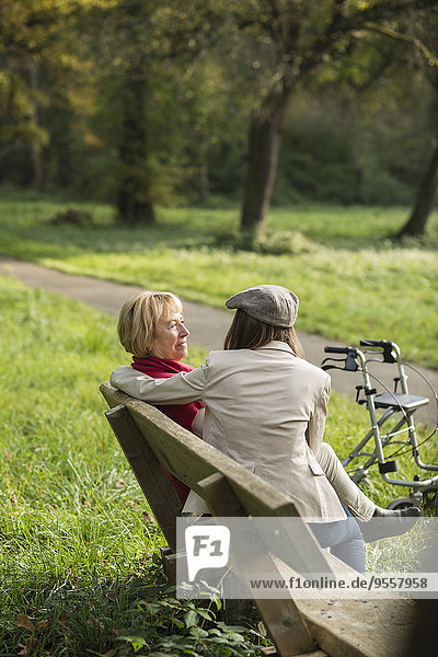 Seniorin und Enkelin auf einer Parkbank sitzend