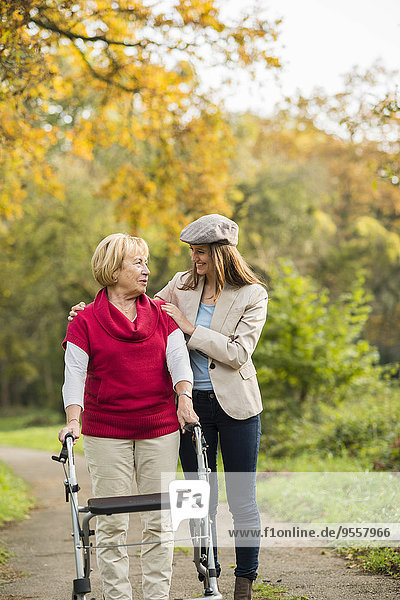 Senior woman and her adult granddaughter walking together in autumnal park