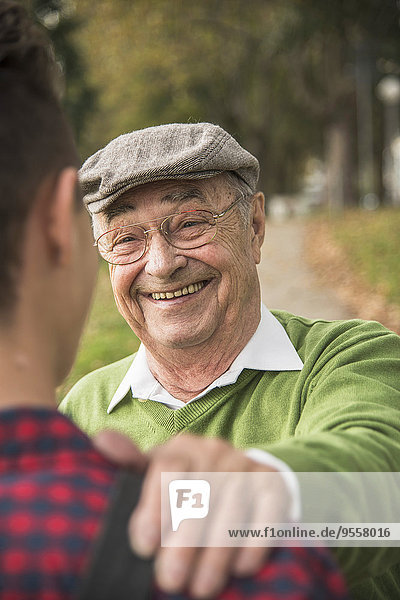 Älterer Mann lächelt erwachsenen Enkel an.