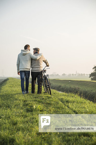 Senior Mann und Enkel in ländlicher Landschaft mit Fahrrad