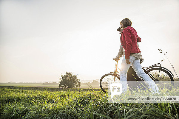 Senior man and daughter in rural landscape with bicycle