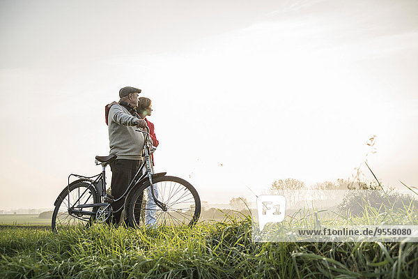 Senior Mann und Tochter in ländlicher Landschaft mit Fahrrad