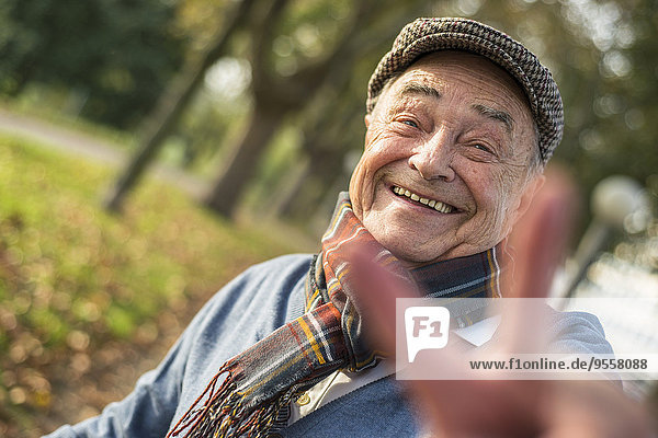 Portrait of happy senior man outdoors doing victory sign