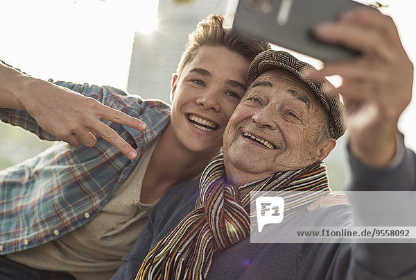 Glücklicher älterer Mann  der einen Selfie mit Enkel nimmt.