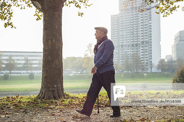 Ein älterer Mann  der am Flussufer spazieren geht.
