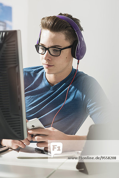 Junger Mann am Schreibtisch mit Kopfhörer