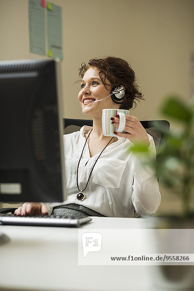 Lächelnde junge Frau im Büro mit Headset