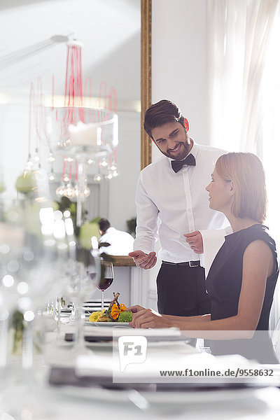 Kellner serviert Abendessen für die Frau in einem eleganten Restaurant.