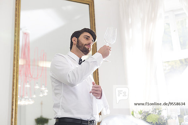 Eleganter Kellner im Restaurant mit Blick auf das Weinglas
