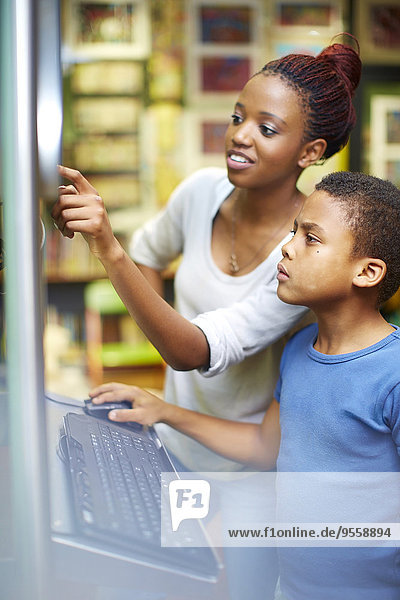Junge Frau und Junge mit Computer in der Bibliothek