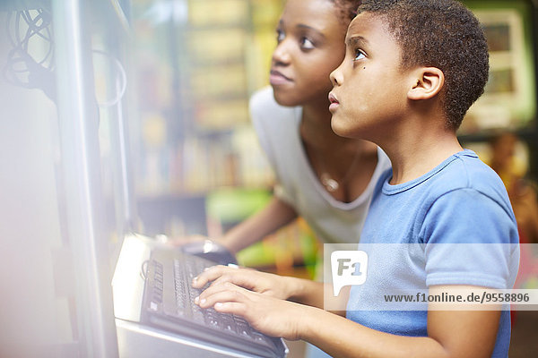 Young woman and boy using computer in library