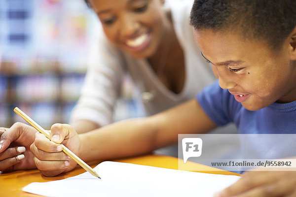 Young woman teaching boy writing on paper
