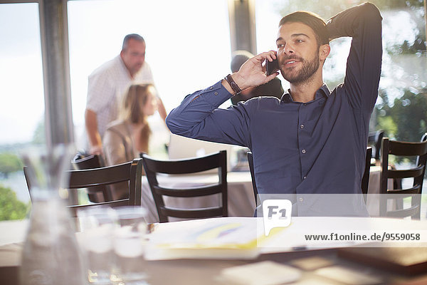 Portrait eines Geschäftsmannes beim Telefonieren mit dem Smartphone im Restaurant