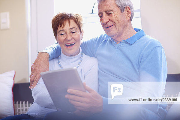 Glückliches Seniorenpaar mit digitalem Tablett zu Hause