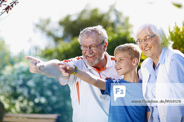 Großeltern mit Enkel im Park  der mit den Fingern zeigt