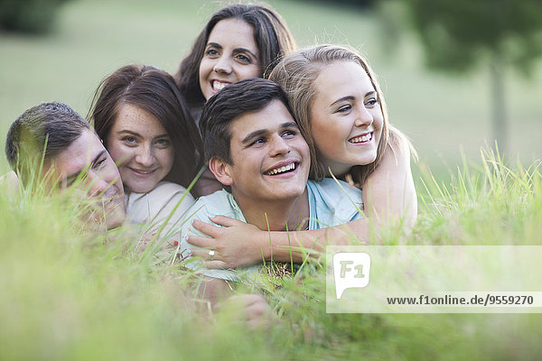 Five happy friends crouching on a meadow