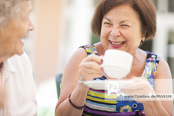 Zwei glückliche Seniorinnen  die zusammen Kaffee trinken.